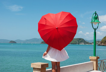 young girl with a red umbrella on the waterfront