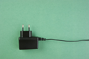 black charger adapter with plug on the green background