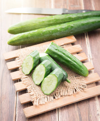 Cucumber and slices on wood background.