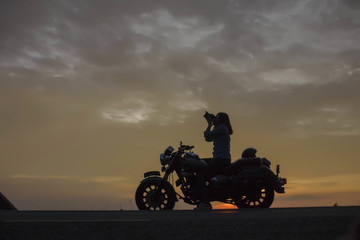 Fototapeta na wymiar biker girl and classic motorcycle at sunse 