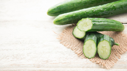 Cucumber and slices on wood background.