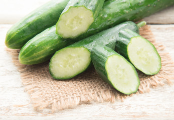 Cucumber and slices on wood background.
