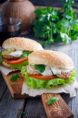 Homemade hamburger with beef, onions, tomatoes, salad and cheese on a wooden board, selective focus