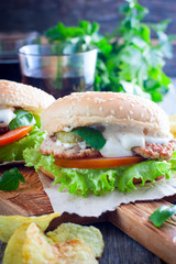 Homemade hamburger with beef, onions, tomatoes, salad and cheese on a wooden board, selective focus