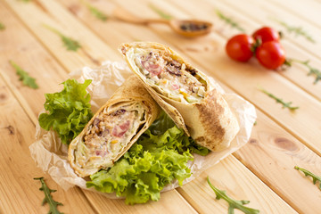 Burritos wraps with meat, beans and vegetables on wooden board