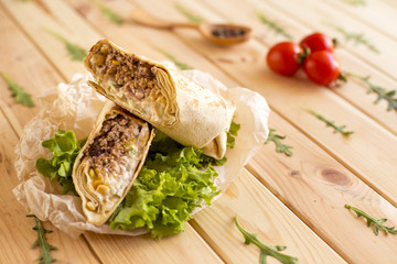 Burritos with minced meat and fresh vegetables close-up on the table
