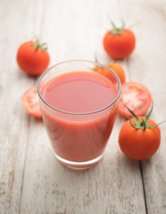Glass of tomato juice on wooden table