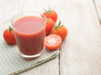Glass of tomato juice on wooden table