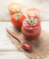 Tomato sauce, ketchup in glass jar on wood background