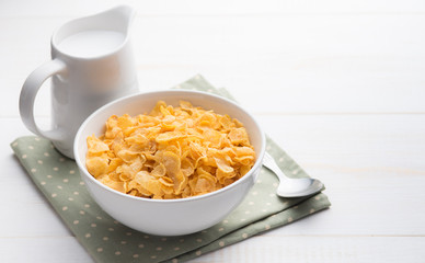 Corn flakes with jug of milk on table wooden