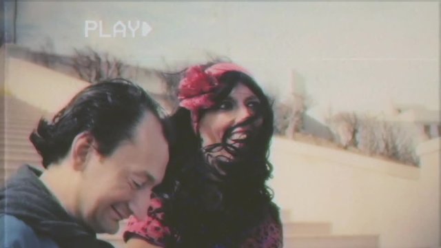 Fake VHS tape: an ugly man brings her blindfolded fiancée to a beautiful place, makes a marriage proposal with a ring, kneeling down. The perplexed girl stalls proposing to take a picture.
