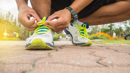 Runner man tying running shoes laces getting ready for race on road.