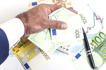 Concept of stock exchange profits. Stock market prices charts, 100,50,200 euro bills and black pen on the diagram. Businessman hand in suit with euro bills cash. Macro image.