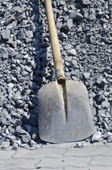 Schaufel vor grauem Splitt - Symbolfoto für Arbeit