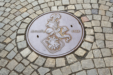 Manhole cover on cobbled road in Malmo Sweden.