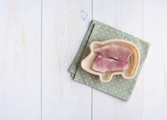 bowl of pig shape with raw pork tenderloin on wood