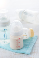 baby bottle and milk with pacifier on a white wood