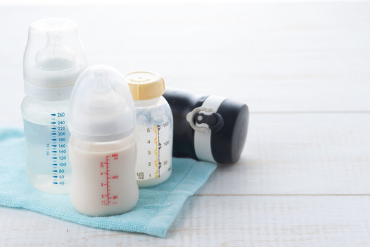 baby bottle and milk with pacifier on a white wood