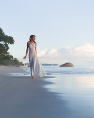 Fototapeta na wymiar Beautiful, sexy blonde woman walks at tropical beach, long dress