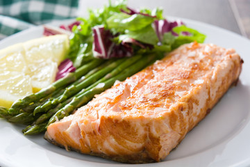 Grilled salmon fillet with asparagus and salad in plate on wooden table

