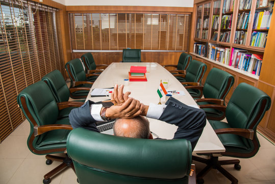 Senior Indian Businessman Relaxing In Chair At Office Or Conference Room Alone