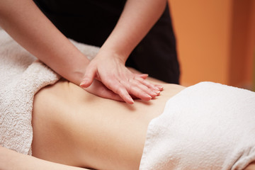 Obraz na płótnie Canvas A woman receiving a belly massage at spa salon