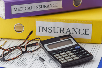 Clean insurance form, folders, pen, glasses and calculator