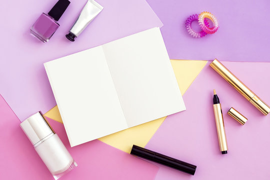 Woman beauty products and blank notepad top view. Colorful pink, purple background, copy space. Fashion blogger concept