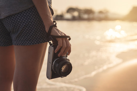 Young woman traveller with retro camera on the beach