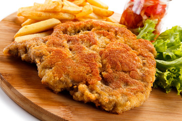 Fried pork chop with french fries on cutting board