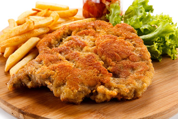 Fried pork chop with french fries on cutting board