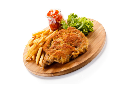 Fried pork chop with french fries on cutting board