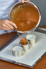 The cook pours the dough into forms for making cupcakes