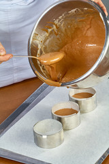 The cook pours the dough into forms for making cupcakes