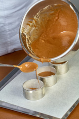 The cook pours the dough into forms for making cupcakes