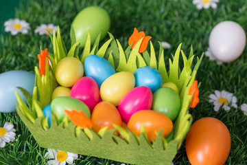 bunte plastik ostereier in einem filz nest auf kunstrasen