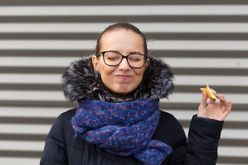 Beautiful girl eagerly eats a hamburger on the street