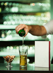 Mid section of bartender pouring beer in a glass at bar counter