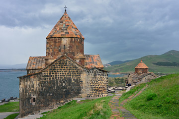Fototapeta na wymiar The tourists visit Sevanavank Monastery, located on Sevan Peninsula, among the bright green hills