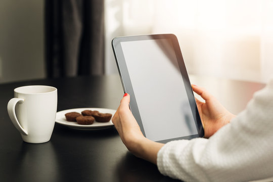 woman sitting by the the table at home and using digital e-book reader