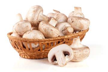 Champignon mushrooms in a wicker basket isolated on white background