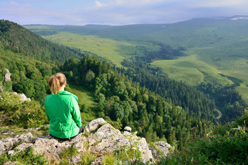 Fototapeta na wymiar girl sitting on the edge of the cliff. Panoramic view of the plateau Lanonaki.
