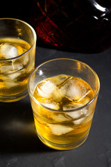 Whiskey with ice in glasses on a black background.