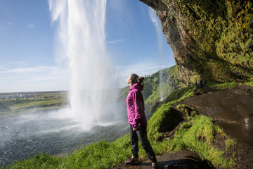 Woman under Seljalandsfoss waterfall, Iceland.