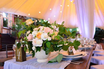 Wedding. Banquet. The chairs and table for guests, decorated with candles, served with cutlery and crockery and covered with a tablecloth.