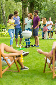 Friends standing beside barbecue grill