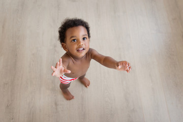 child standing on a wood floor looking up with arms extended