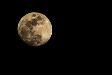 A clear golden moon with a lot of craters.