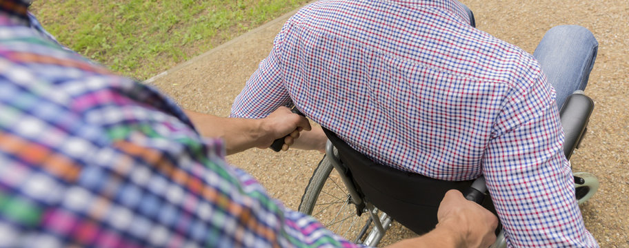 Man helping friend on wheelchair