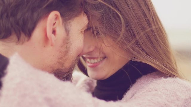 Man and woman nose to nose looking at each other in love romantic moment in front of the ocean slow motion extreme closeup